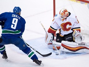 Calgary Flames' goalie Chad Johnson, right, stops Vancouver Canucks' Jack Skille during the second period of a pre-season NHL hockey game in Vancouver, B.C., on Thursday October 6, 2016.