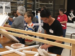 Joel Van den Berg, 10 and Hillhurst School teacher Angelo Law help prepare crosses in office space donated by Raytheon Canada Limited. The crosses will be placed along Memorial Drive next weekend for the annual Field of Crosses Memorial Project.
