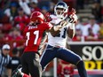 Toronto Argonauts' Vidal Hazelton, makes a catch as Calgary Stampeders' Joshua Bell looks on during first quarter CFL football action in Calgary, Monday, July 13, 2015.