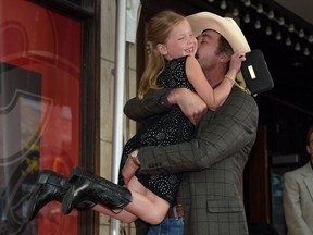 Julia Maren Baker, 7, is scooped up for a hug by Heartland co-star Shaun Johnston outside Flames Central in Calgary during a celebration of the show's 10th year in September at the Calgary International Film Festival.