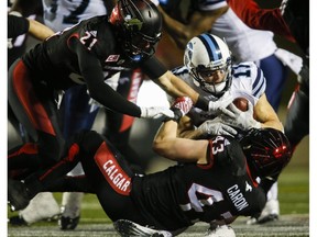 Toronto Argonauts' Devon Wylie, centre, is brought down by Calgary Stampeders' Adam Berger, left, and Max Caron during second half CFL football action in Calgary, Friday, Oct. 21, 2016.