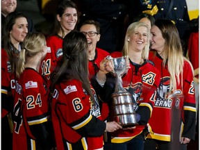 Members of the Calgary Inferno bring their championshiop hardware onto the ice before NHL action between the Calgary Flames and Winnipeg Jets in Calgary, Alta., on Wednesday, March 16, 2016. The Inferno won the CWHL title.