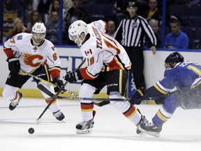 Calgary Flames' Matthew Tkachuk (19) controls the puck as St. Louis Blues' Jaden Schwartz, right, defends and Michael Frolik, of the Czech Republic, watches during the first period of an NHL hockey game Tuesday, Oct. 25, 2016, in St. Louis.