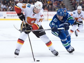 Vancouver Canucks' Philip Larsen, right, of Denmark, checks Calgary Flames' Micheal Ferland during the first period of a pre-season NHL hockey game in Vancouver, B.C., on Thursday October 6, 2016.