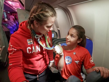 Olympic gold medallist Erica Wiebe shows her medal to Ava Dustyhorn, 8, while chatting with kids on board an Air Canada flight to Los Angeles on Wednesday, Oct. 19, 2016. Dreams Take Fight Calgary took 150 kids deserving a break from difficult situations for a one-day trip to the Magical Kingdom. It was Air Canada's 24th year for its charity event. Lyle Aspinall/Postmedia Network