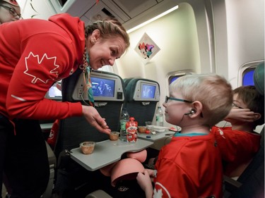 Olympic gold medallist Erica Wiebe shows her medal while chatting with kids on board an Air Canada flight to Los Angeles on Wednesday, Oct. 19, 2016. Dreams Take Fight Calgary took 150 kids deserving a break from difficult situations for a one-day trip to the Magical Kingdom. It was Air Canada's 24th year for its charity event. Lyle Aspinall/Postmedia Network