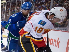 Calgary Flames' Linden Vey, far right, battles for the puck with Vancouver Canucks' Luca Sbisa in Vancouver, B.C., on Thursday October 6, 2016.