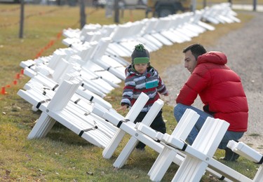 Ashkan Shirdast and his son Kiumars, 3 yrs, examine a large amount of crosses during the set-up at the Field of Crosses Memorial Project in Calgary, Alta on Saturday October 22, 2016 near Memorial Dr and Centre St NW. Starting November 1st to November 11th, over 3,200 crosses are being displayed on a 5 acre city park in military cemetery formation to memorialize southern Alberta soldiers who were killed in action.  Each cross is inscribed with the name, age at death, rank, regiment and date of death of a soldier who lost his or her life in a foreign land, fighting for the freedoms we all enjoy today. Jim Wells/Postmedia