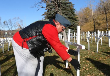 Steve Merritt places a photo of his brother Jim on his cross during the set-up at the Field of Crosses Memorial Project in Calgary, Alta on Saturday October 22, 2016 near Memorial Dr and Centre St NW. Starting November 1st to November 11th, over 3,200 crosses are being displayed on a 5 acre city park in military cemetery formation to memorialize southern Alberta soldiers who were killed in action.  Each cross is inscribed with the name, age at death, rank, regiment and date of death of a soldier who lost his or her life in a foreign land, fighting for the freedoms we all enjoy today. Jim Wells/Postmedia