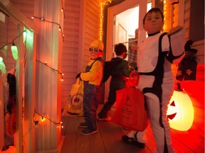 Alex Blake, left, watches as Liam Brown pumps his fist after receiving a can of coke while trick or treating in the community of Country Hills in Calgary on Halloween Saturday, Oct. 31, 2015. (Aryn Toombs/Calgary Herald) (For Entertainment story by NONE) 00069692A SLUG: 1031 Trick or Treat