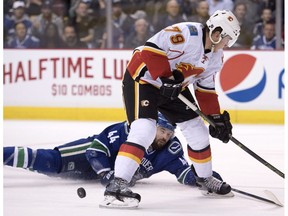 Vancouver Canucks defenceman Erik Gudbranson (44) fights for control of the puck with Calgary Flames centre Micheal Ferland (79) during first period NHL action, in Vancouver on Saturday, Oct. 15, 2016.