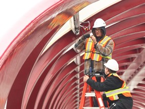 Workers install new overhead LED lighting on the Peace Bridge.