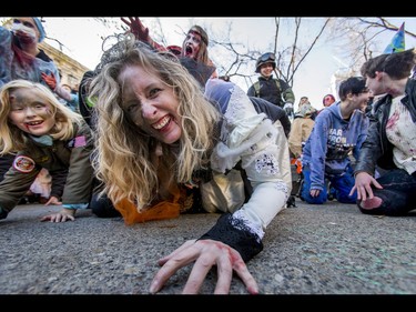 Stacey O'Sullivan crawls for a photo before the Zombie Walk in downtown Calgary, Alta., on Saturday, Oct. 15, 2016. The Zombie Walk is an annual event held mostly for fun but also to raise money and cash for the Calgary Food Bank. Lyle Aspinall/Postmedia Network