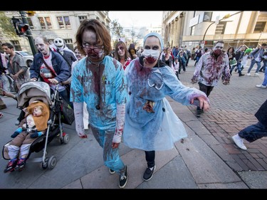 Kate Neville (R) and cuddles Brielle Ranger trudge through the Zombie Walk in downtown Calgary, Alta., on Saturday, Oct. 15, 2016. The Zombie Walk is an annual event held mostly for fun but also to raise money and cash for the Calgary Food Bank. Lyle Aspinall/Postmedia Network