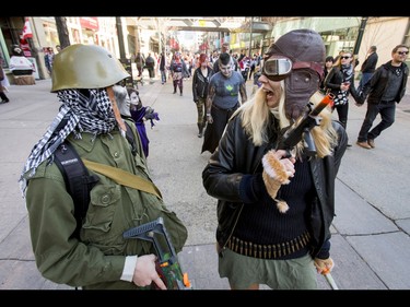 Zombie hunters Sarah-Joy Goode and Liam Geddes watch their six during the Zombie Walk in downtown Calgary, Alta., on Saturday, Oct. 15, 2016. The Zombie Walk is an annual event held mostly for fun but also to raise money and cash for the Calgary Food Bank. Lyle Aspinall/Postmedia Network