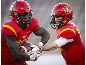 University of Calgary Dinos quarterback Adam Sinagra, right, hands the ball off to Jeshrun Antwi during second half CIS Hardy Cup football action against the University of British Columbia Thunderbirds in Calgary, Saturday, Nov. 12, 2016. The Dinos face  the St. Francis Xavier X-Men in Saturday's national semifinal.