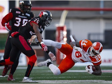 B.C. Lions' Emmanuel Arceneaux, right, is brought down by Calgary Stampeders' Tommie Campbell, centre, and Charleston Hughes during first quarter CFL Western Final football action, in Calgary on Sunday, Nov. 20, 2016.