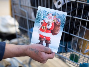 A homeless man who did not wish to identified holds up a blank Christmas card he found while collecting bottles in Calgary's beltline on Monday November 21, 2016.