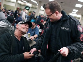 Calgary Police Service Acting Inspector Frank Cattoni gives a pair of socks to man who goes by Mo-J at the Calgary Drop-In Centre on Tuesday November 29, 2016. Over 12,000 pairs of warm socks were collected by Calgarians to help out the homeless.