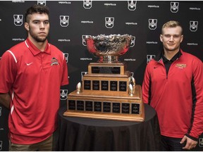 Calgary Dinos quarterback Jimmy Underdahl, right, and Laval Rouge Et Or quarterback Hugo Richard stand next to the Vanier Cup during a media conference in Hamilton, Ont., on November 24, 2016.