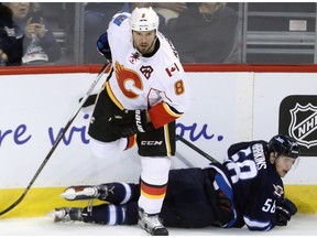 Calgary Flames' Nicklas Grossman (8) steps over Winnipeg Jets' Jansen Harkins (58) during first period pre-season NHL hockey in Winnipeg, Tuesday, September 27, 2016. Grossman will draw into the lineup against the Los Angeles Kings on Saturday.