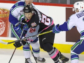 Calgary Hitmen Carsen Twarynski pushes between Swift Current Broncos Kade Jensen and Tyler Steenbergen in WHL action at the Scotiabank Saddledome in Calgary, Alberta, on Saturday, November 5. Mike Drew/Postmedia