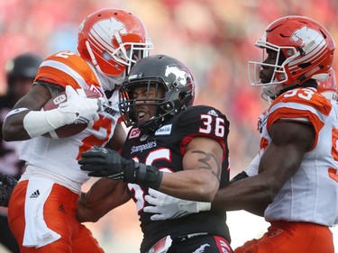 Calgary Stampeders  Glenn Love, middle, blocks BC Lions Chris Rainey. left, during CFL Western Final action at McMahon Stadium in Calgary, Alta.. on Sunday November 20, 2016. Leah hennel/Postmedia