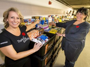 Leanne Courchesne (L), group lead of community affairs with Cenovus, shows off 12,000 pounds of donated food with Marie Blackburn, manager of the Veterans Food Bank, at the Bow loading dock in downtown Calgary, Alta., on Tuesday, Nov. 8, 2016. In addition to the food bank donation, Cenovus donated $1.6 million to various organizations as part of its seventh annual Thanks and Giving campaign. Lyle Aspinall/Postmedia Network