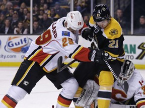 Calgary Flames defenseman Deryk Engelland (29) tries to clear Boston Bruins left wing Loui Eriksson (21) away from the net as Flames goalie Karri Ramo looks to cover the puck during the second period of an NHL hockey game in Boston, Thursday, March 5, 2015.