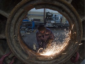 A worker works on a part from a rock crusher at Universe Machine, an Edmonton manufacturing company.