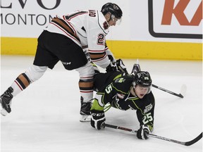 Edmonton's Lane Bauer (right) is knocked off his skates by  Calgary's Matteo Gennaro during the first period of a WHL game between the Edmonton Oil Kings and the Calgary Hitmen at Rogers Place in Edmonton, Alberta on Friday, October 28, 2016.