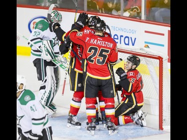 Goal-scorer Johnny Gaudreau of the Calgary Flames climbs out of the Dallas Stars' net near teammates Brett Kulak, Sean Monahan and Freddie Hamilton, and Dallas Stars goalie goalie Kari Lehtonen and defender Johnny Oduya during NHL action in Calgary, Alta., on Thursday, Nov. 10, 2016. Lyle Aspinall/Postmedia Network
