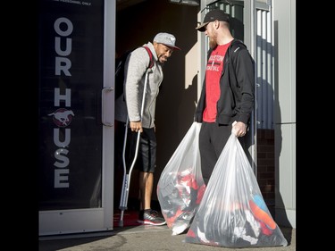 Calgary Stampeders quarterback Bo Levi Mitchell helps injured teammate Deron Mayo with the door and his bags at McMahon Stadium in Calgary, Alta., on Tuesday, Nov. 29, 2016. The Stamps were cleaning out their lockers two days after losing the Grey Cup to Ottawa in Toronto. Lyle Aspinall/Postmedia Network