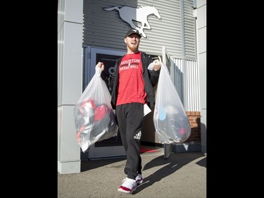 Calgary Stampeders quarterback Bo Levi Mitchell carries injured teammate Deron Mayo's bags at McMahon Stadium in Calgary, Alta., on Tuesday, Nov. 29, 2016. The Stamps were cleaning out their lockers two days after losing the Grey Cup to Ottawa in Toronto. Lyle Aspinall/Postmedia Network