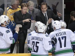 Vancouver Canucks head coach John Tortorella, top right, and assistant coach Glen Gulutzan, top left, talk with their players in the third period of an NHL hockey game against the Nashville Predators Tuesday, Dec. 3, 2013, in Nashville, Tenn. The Canucks won 3-1.