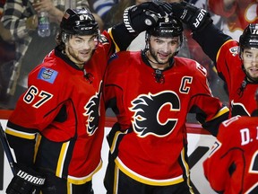 Calgary Flames' Mark Giordano, centre, celebrates his goal with teammates Michael Frolik, left, from the Czech Republic, and Josh Jooris during third period NHL hockey action against the Winnipeg Jets in Calgary, Wednesday, March 16, 2016.