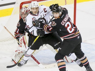 Matteo Gennaro (R) of the Calgary Hitmen jostles with Adam Musil of the Red Deer Rebels in front of Hitmen goalie Cody Porter during WHL action at the Scotiabank Saddledome in Calgary on Nov. 22, 2016.