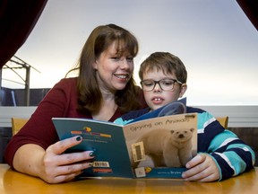 Victoria Wychick helps her son Joshua with some school reading at home in Calgary, Alta., on Wednesday, Nov. 23, 2016. Joshua, who has learning disabilities, may have to switch schools after the Calgary Catholic School District has proposed to close St Anthony School and move programming to a larger school several kilometres away. Lyle Aspinall/Postmedia Network