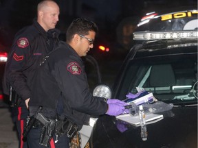 Police officers sort through items at the scene of the stabbing Thursday evening November 17, 2016 in the 100 block of Coral Springs Close NE.