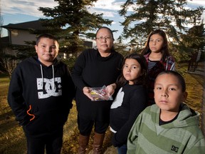 Amanda Goodstoney holds chocolate bars with needles in them while she stands with her children from left; Madden,10,  Makayla, 7, Cheyanne, 12 and Jonathan, 6 in the Gleneagles neighbourhood in Cochrane. Someone in the neighbourhood placed the chocolate bars in the children's candy bags while they were trick or treating in the area on Halloween. GAVIN YOUNG/POSTMEDIA