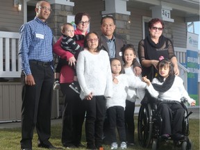 Gezai Gebrekidan, left, and the Dumlao family, from left, mom Suzanne holding Jacob, Zoe, dad Jeffrey, Finley, Carmella and Autumn, along with grandmother Lili Desjardins, infront of their new home, a  wheelchair accessible duplex, through Habitat for Humanity Southern Alberta in the northeast community of Redstone by Qualico Communities.