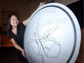 Amy Choi poses with the mock up of the new Royal Canadian Mint 10 cent coin's tails side which will carry her artwork Wings of Peace". She was part of a ceremony inCalgary at the Glenbow Museum Wednesday November 2, 2016 which coincided with simultaneous unveiling of coins across the the country. (Ted Rhodes/Postmedia Calgary )