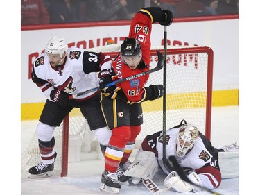 Garnet Hathaway of the Calgary Flames is held up in front of the Arizona Coyiotes  goalie Mike Smith by defenseman Alex Goligoski during the first period at the Saddledome Wednesday November 16, 2016.