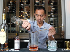 Royale Brasserie Francaise bartender James Nguyen mixes and presents a Sazerac cocktail in the bar on 17th Avenue in Calgary. The drink is cognac based.