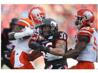 Calgary Stampeders  Glenn Love, middle, blocks BC Lions Chris Rainey. left, during CFL Western Final action at McMahon Stadium in Calgary, Alta.. on Sunday November 20, 2016. Leah hennel/Postmedia