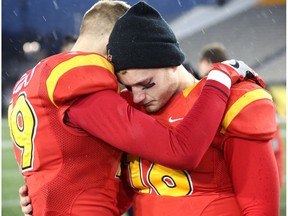Teammates Calgary Dinos starting quarterback Jimmy Underdahl (16) and Michael Klukas (19) hug following their during teams' loss to the Laval Rouge et Or in the U Sports Vanier Cup championship, in Hamilton, Ont., on Saturday, November 26, 2016.