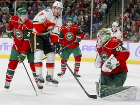 Calgary Flames defenseman TJ Brodie (7) goes airborne as Minnesota Wild goalie Devan Dubnyk (40) makes a save during the second period of an NHL hockey game, Tuesday, Nov. 15, 2016, in St. Paul, Minn. Wild defenseman Ryan Suter (20) is at left. Calgary won 1-0.