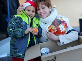 Irma Castaneda and her son Valentino, 5, with their food hamper from the Mustard Seed they picked up at the Montgomery Community Association in Calgary, Alta., on Saturday December 17, 2016. Leah Hennel/Postmedia