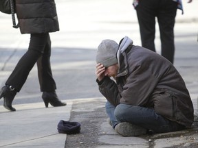 A homeless man looks distraught as he sits on 1 St SW near 7 Ave on Wednesday April 2, 2014.  He left with some change citizens dropped in his hat. Jim Wells/Postmedia Network