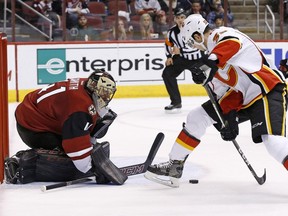 Arizona Coyotes goalie Mike Smith, left, makes a save on a shot by Calgary Flames right wing Alex Chiasson, right, during the first period of an NHL hockey game Thursday, Dec. 8, 2016, in Glendale, Ariz.